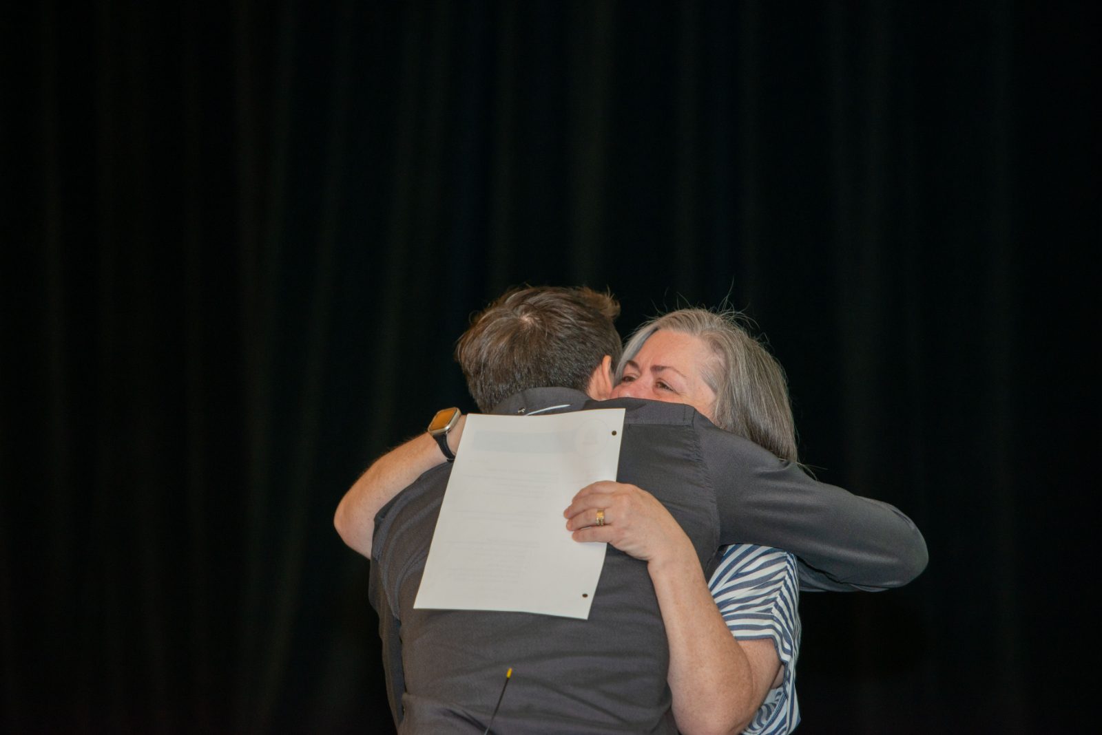 Two people embracing on stage at the National Forum
